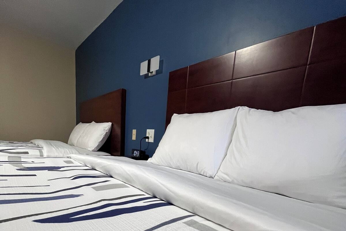 Una habitación de hotel con una cama grande, un cabecero y un reloj fijado a la pared.