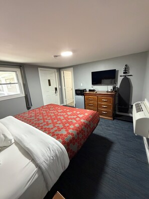 A hotel room with a bed, a dresser, a television, and a window.