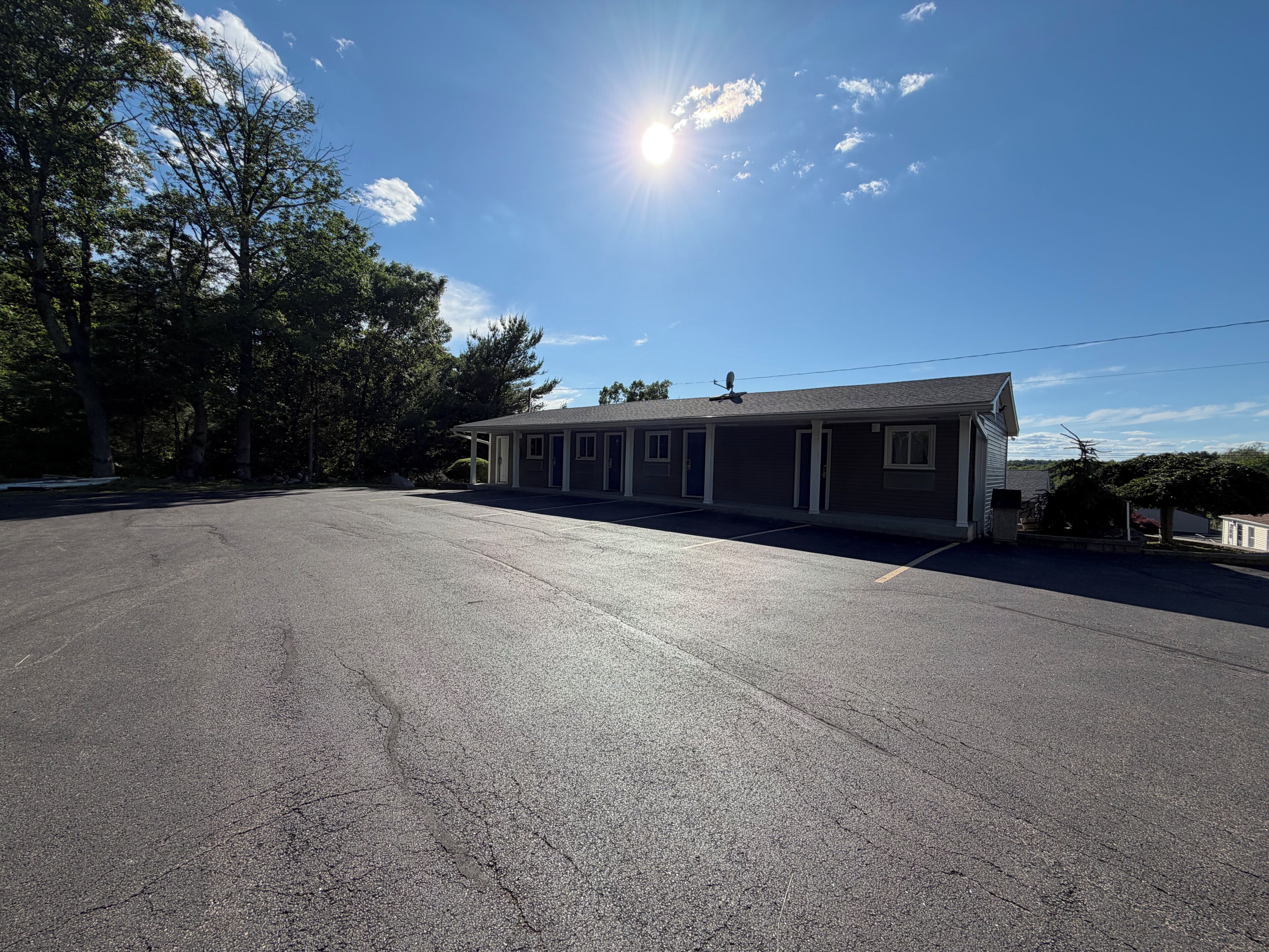 A motel with a parking lot, a single-story building, and a clear sky.