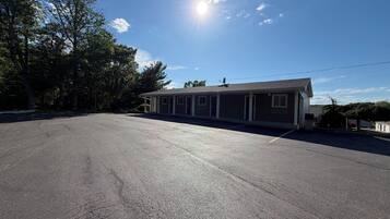 A motel with a parking lot, a single-story building, and a clear sky.