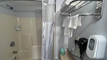 A bathroom with a bathtub, a shower, a towel rack, and a soap dispenser.