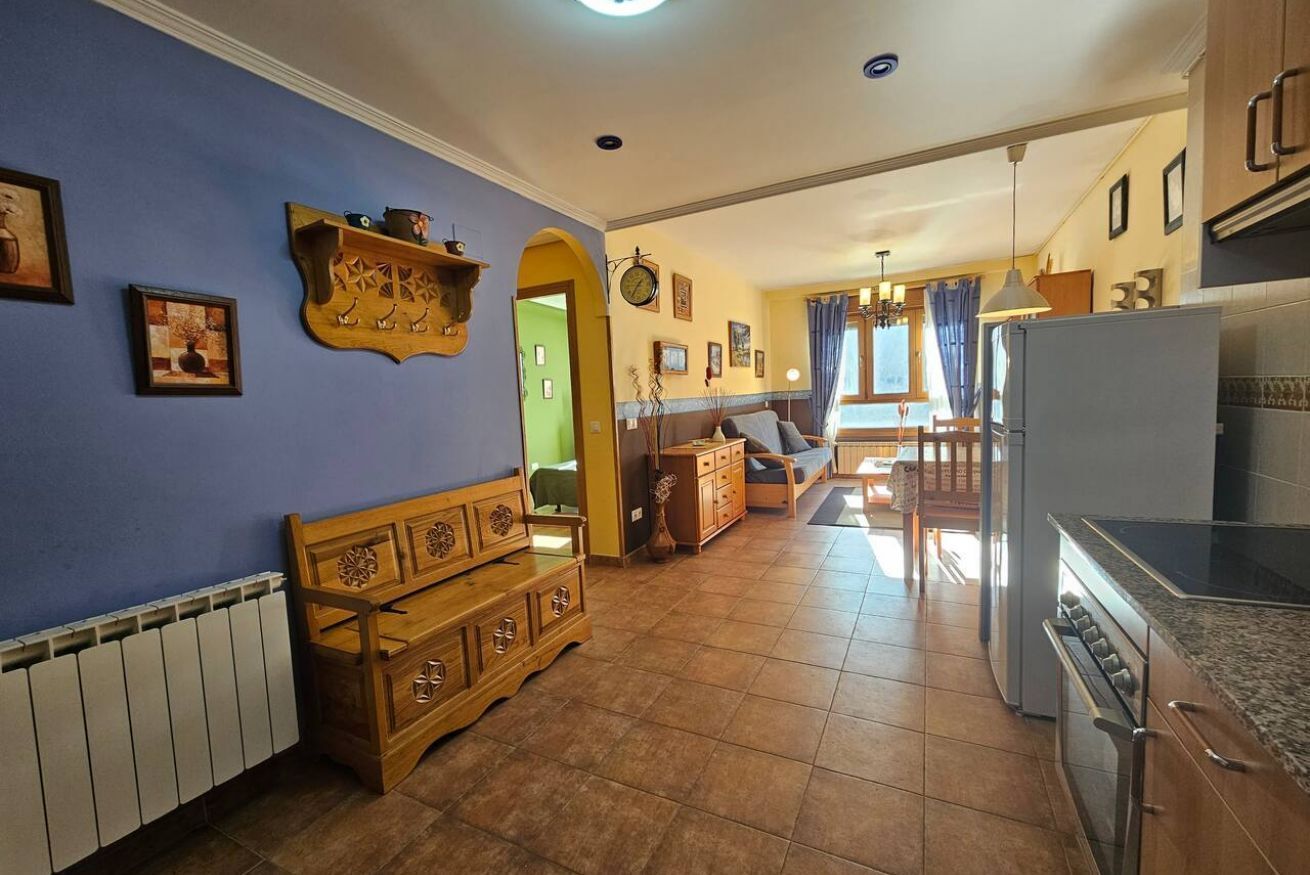 Un grand espace de vie comprenant un banc en bois, une table à manger et une cuisine équipée d’un réfrigérateur et d’un four.