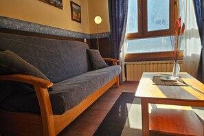 Una stanza con un divano, un tavolo in legno, una lampada da terra e una finestra con tende.