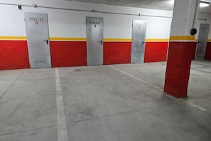 Un parcheggio con pavimenti in cemento e pareti rosse e bianche, con porte numerate 3, 4 e 5.