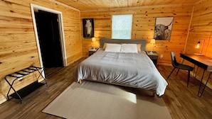 A wooden cabin bedroom with a bed, nightstands, a desk, and a chair. - Family Sized Cabin Near RRG Hiking Trails + Hot Tub - Sleeps 9 (Stanton)