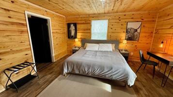 Une chambre dans une cabane en bois, avec un lit, des tables de chevet, un bureau et une chaise.