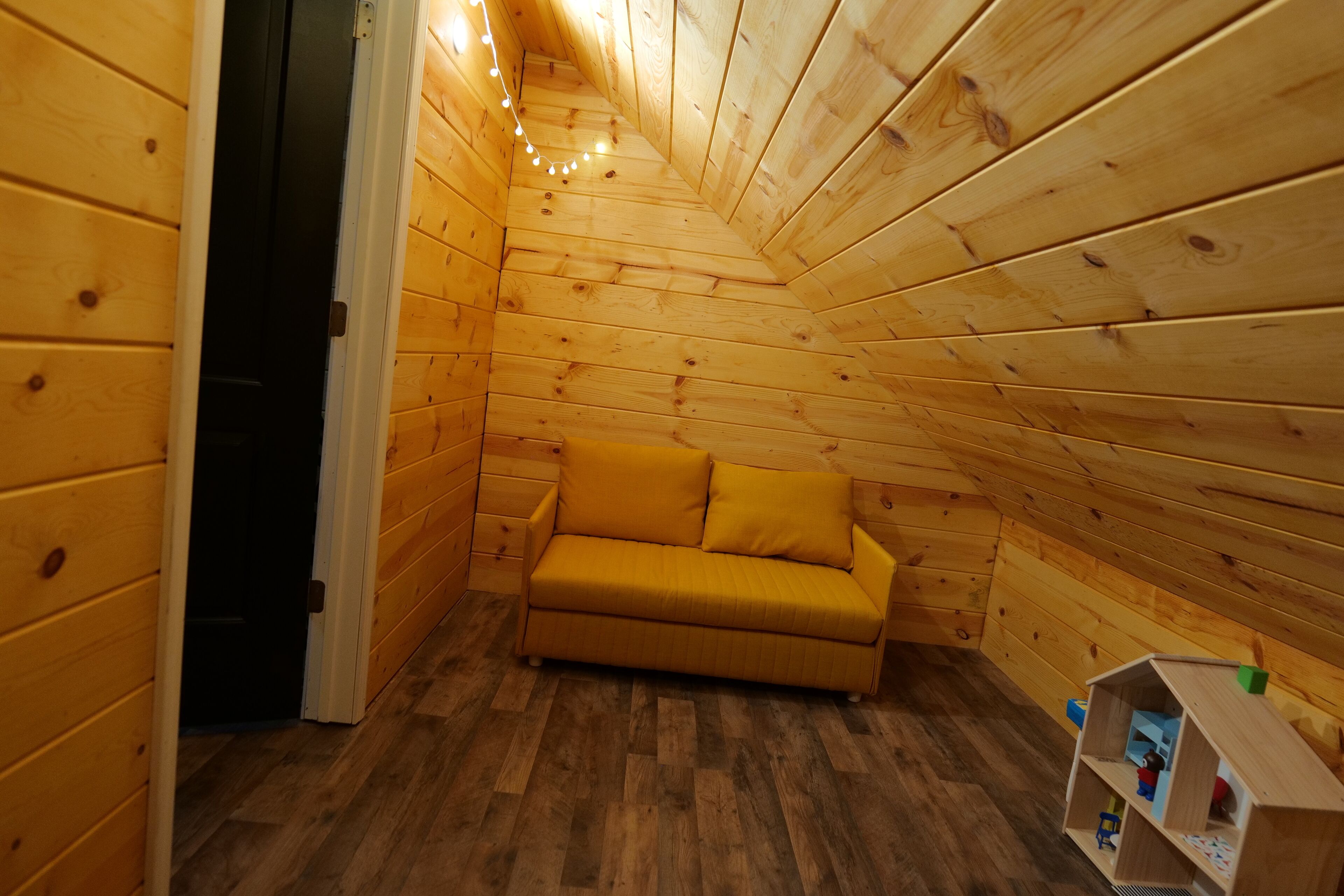 Una cabana de fusta amb un sofà i una petita caseta de joguines.