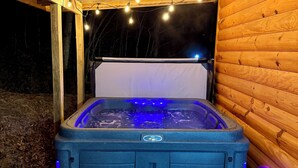 A hot tub with a control panel, surrounded by wooden decking and string lights. - Family Sized Cabin Near RRG Hiking Trails + Hot Tub - Sleeps 9 (Stanton)
