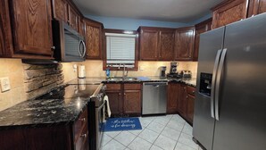 A kitchen with wooden cabinets, a stainless steel refrigerator, a dishwasher, and a coffee maker. - Pet Friendly! Ocean Views/2 king suites/ sleeps 12 (North Topsail Beach)