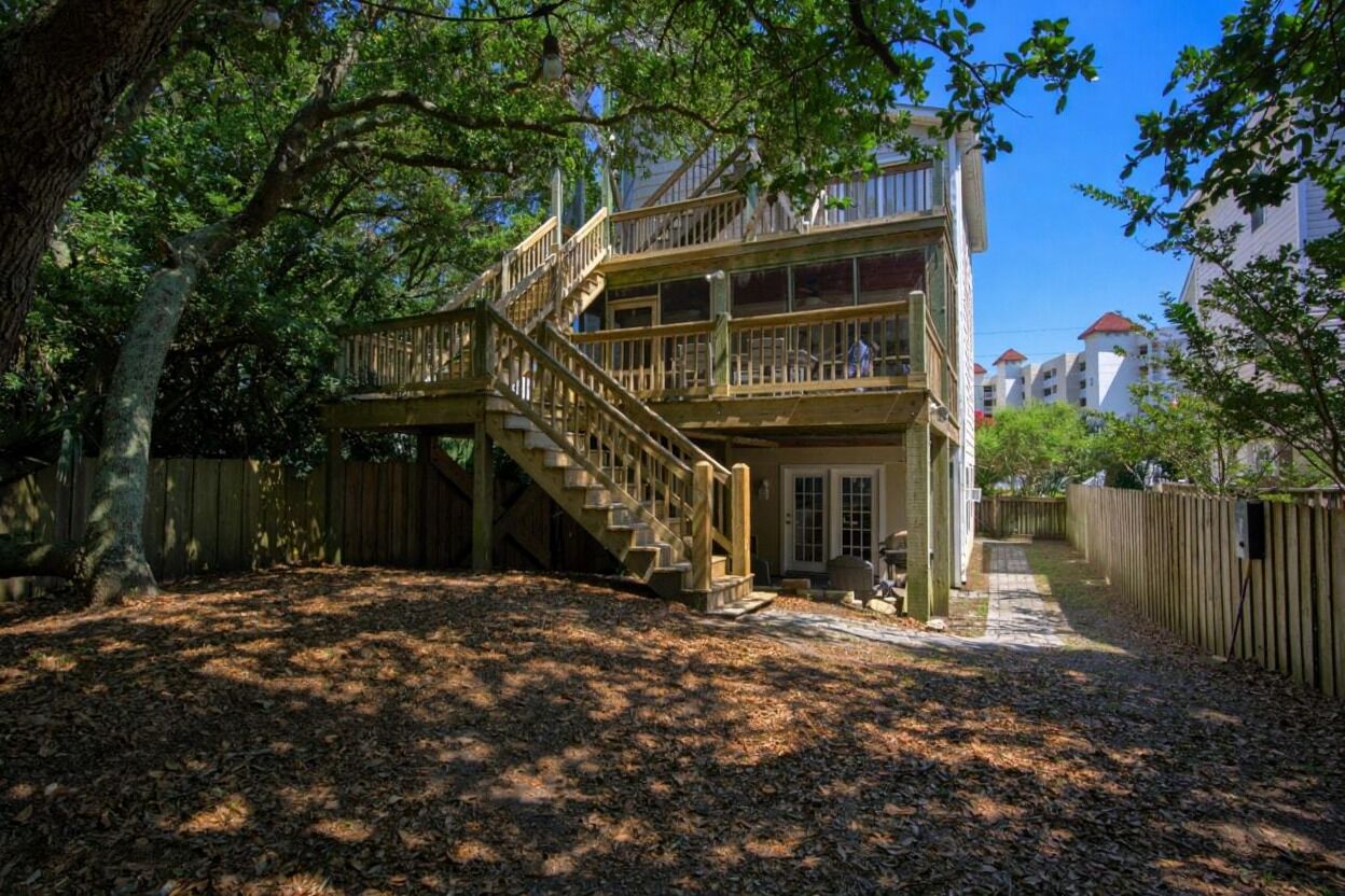 Une maison en bois à deux étages, dotée d’une terrasse en bois et d’un escalier menant à l’étage supérieur.