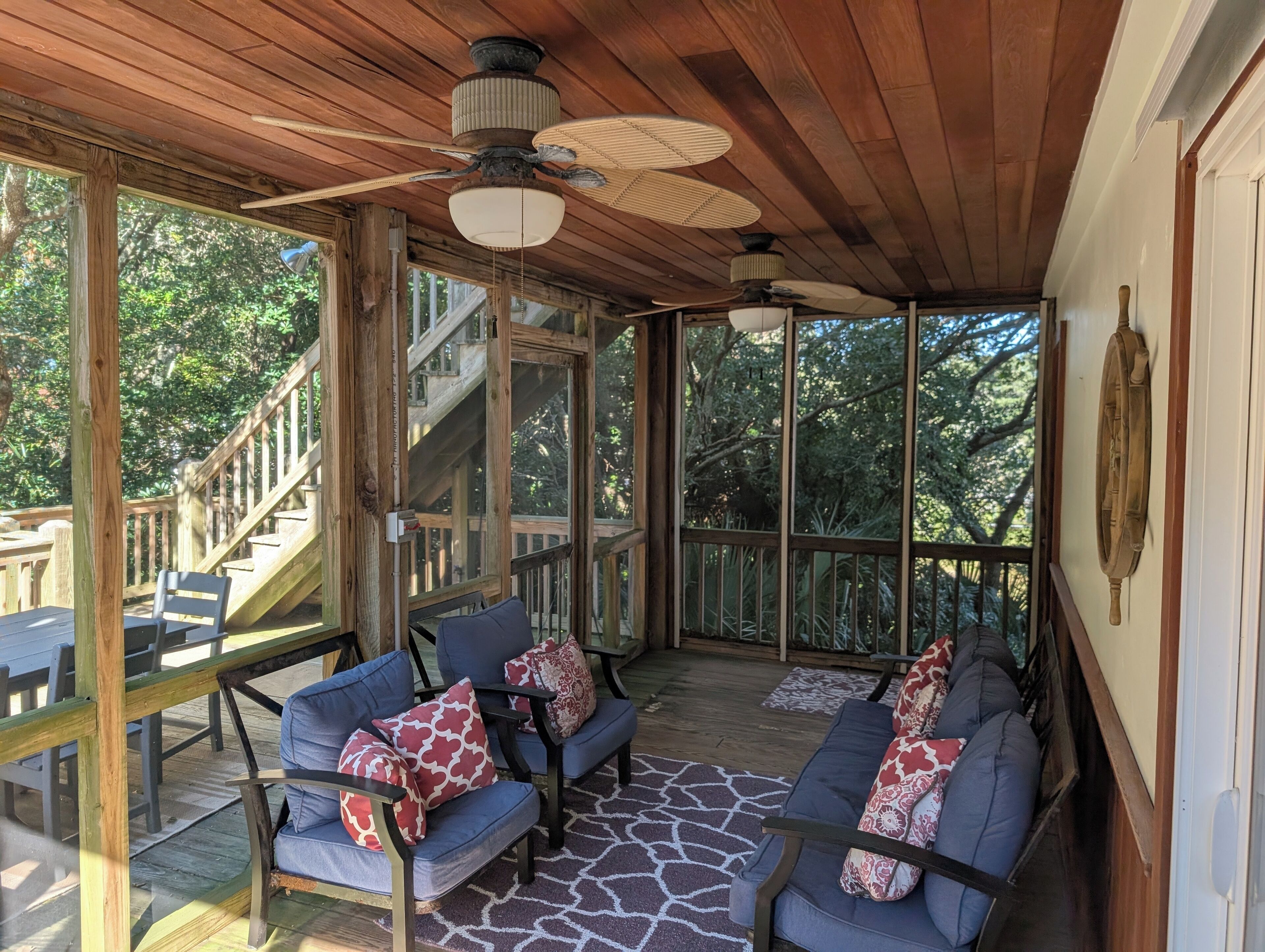 A covered outdoor seating area with wooden furniture and a ceiling fan.