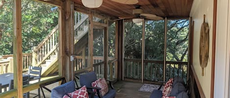 A covered outdoor seating area with wooden furniture and a ceiling fan.