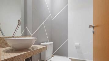 Un baño moderno con lavamanos blanco, inodoro y zona de ducha.
