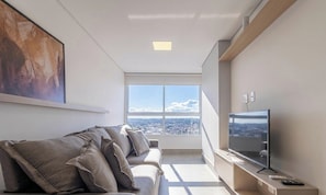 Ein modernes Wohnzimmer mit einer Couch, einem Flachbildfernseher und einem großen Fenster mit Blick auf die Stadt.