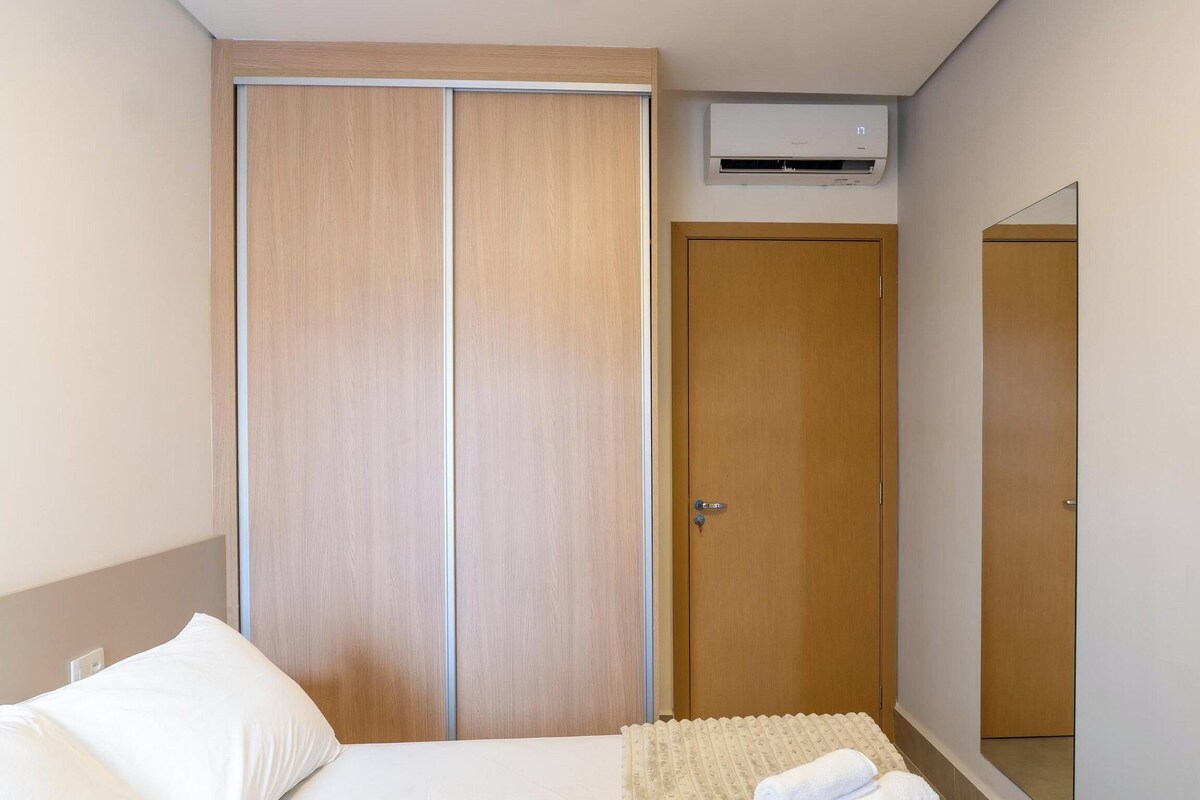 Une chambre à coucher comprenant un lit, une armoire, un miroir et un appareil de climatisation.