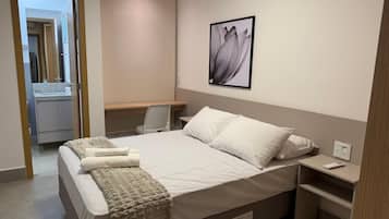Un dormitorio con cama, mesitas de noche, un escritorio y una silla.