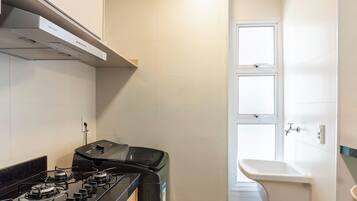 Cocina compacta con estufa a gas, horno empotrado y campana extractora de pared.