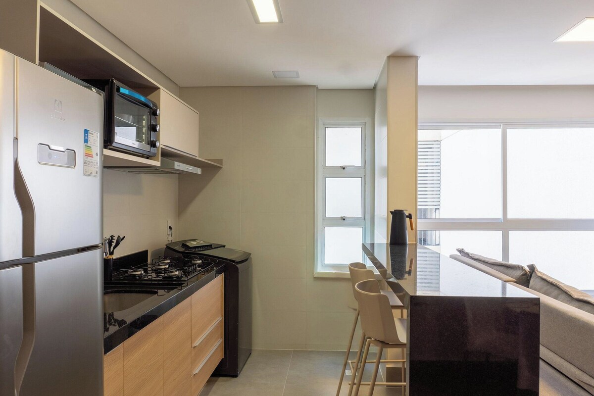 A compact kitchen with a microwave, stove, and a small dining area with a table and chairs.