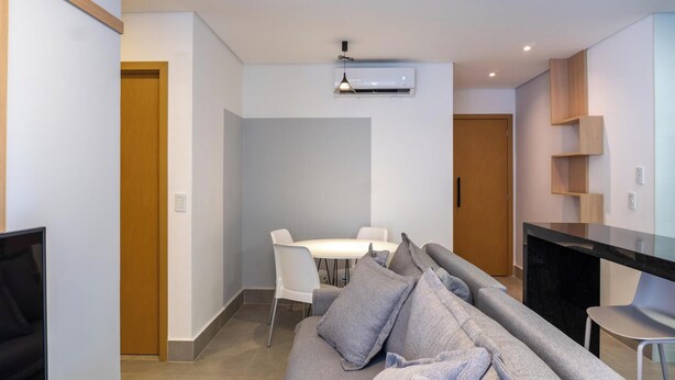 A modern living room with a sofa, a dining table with chairs, and a kitchen area with a countertop and cabinets. - Apts in a Building With Pool and Gym - GRL (Anapolis)