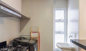 A compact kitchen with a gas stove, a built-in oven, and a window with a view. - Apts in a Building With Pool and Gym - GRL (Anapolis)