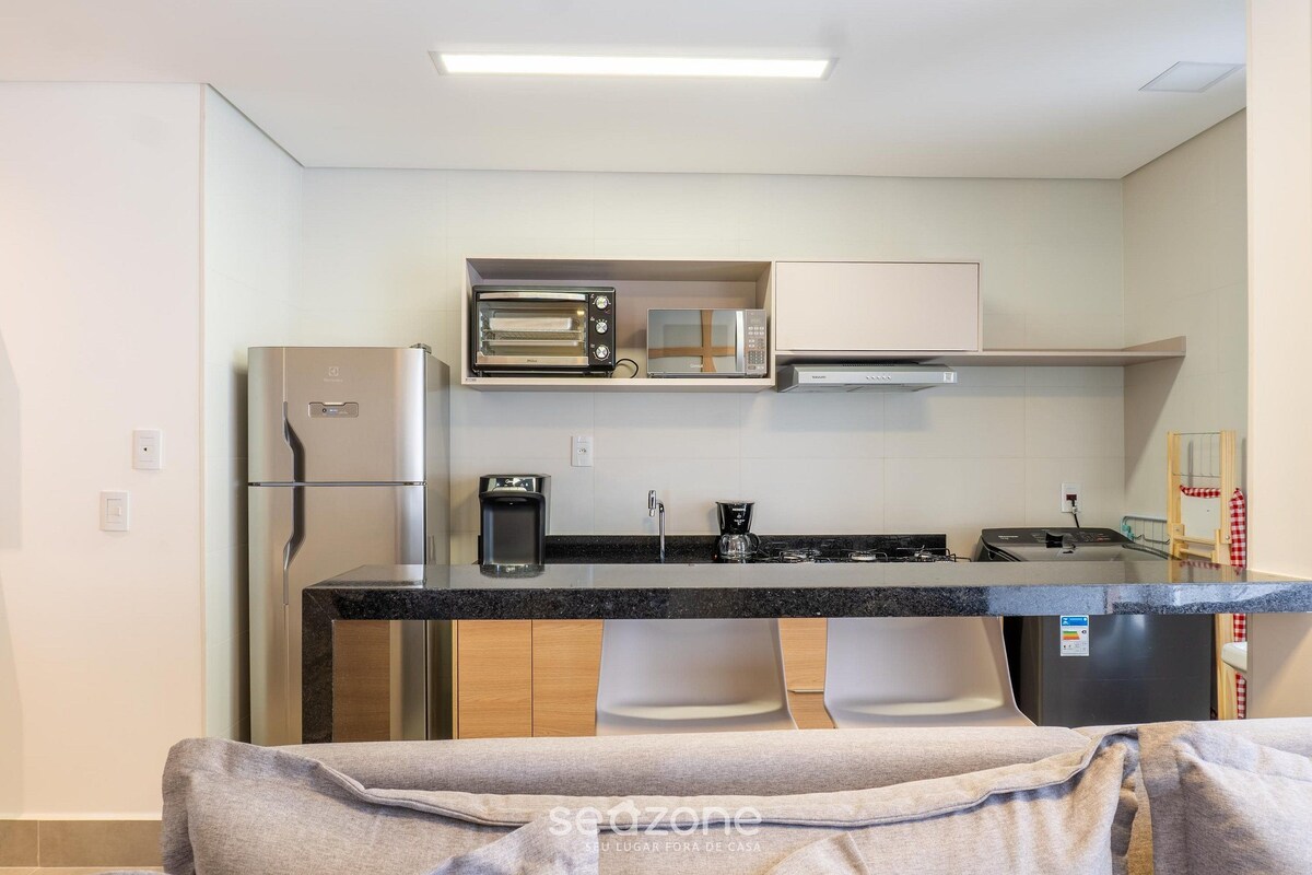 A compact kitchen with a built-in oven, microwave, and coffee maker.