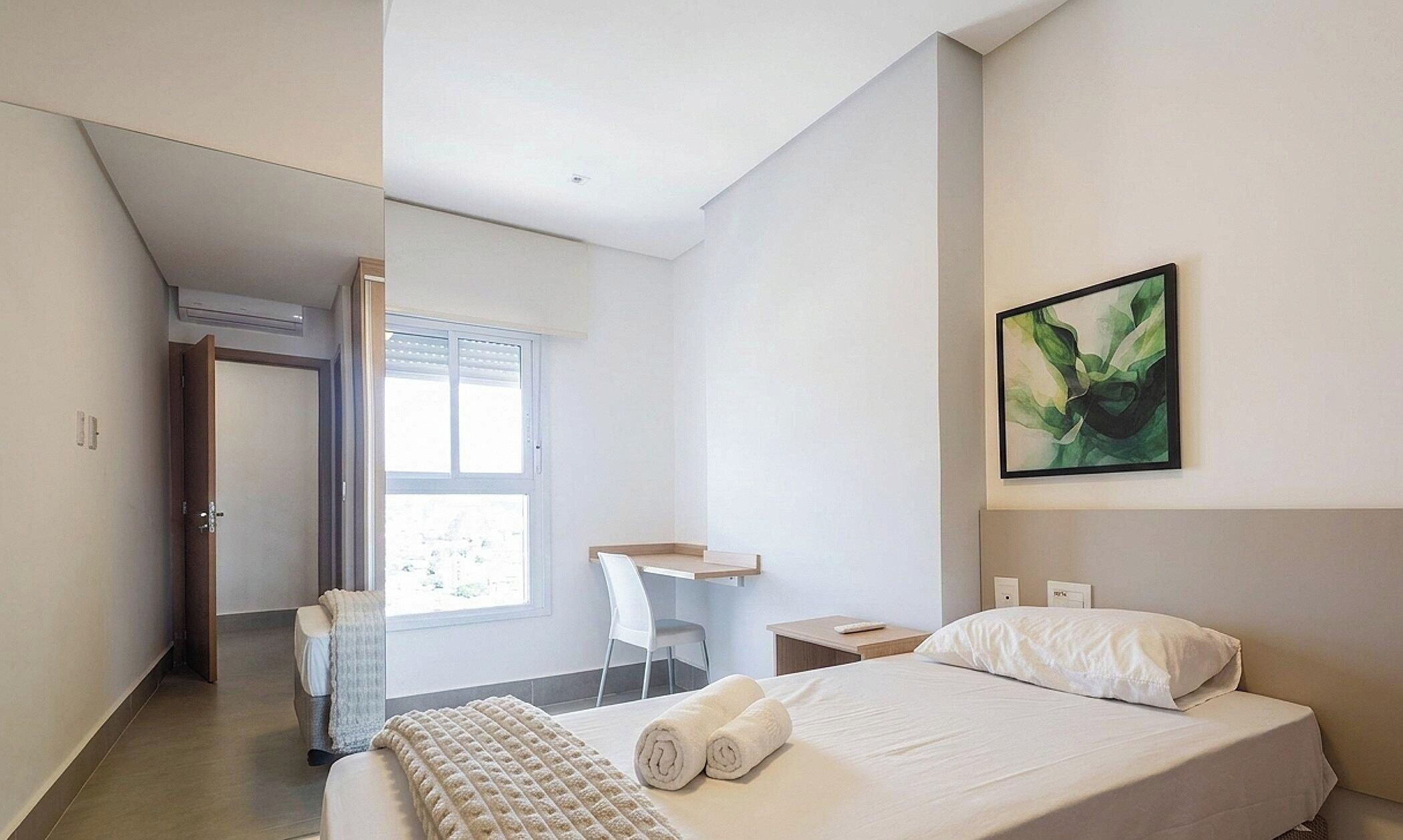 Una habitación de hotel moderna con una cama, un escritorio, una silla y un cuadro en la pared.