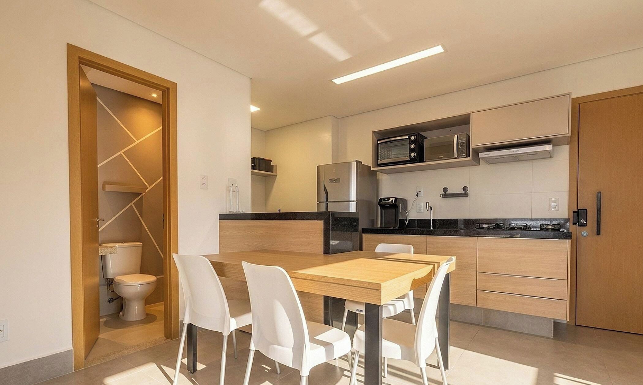 A modern kitchen with a dining area, including a refrigerator, microwave, and a coffee machine.