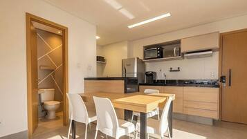 A modern kitchen with a dining area, including a refrigerator, microwave, and a coffee machine.