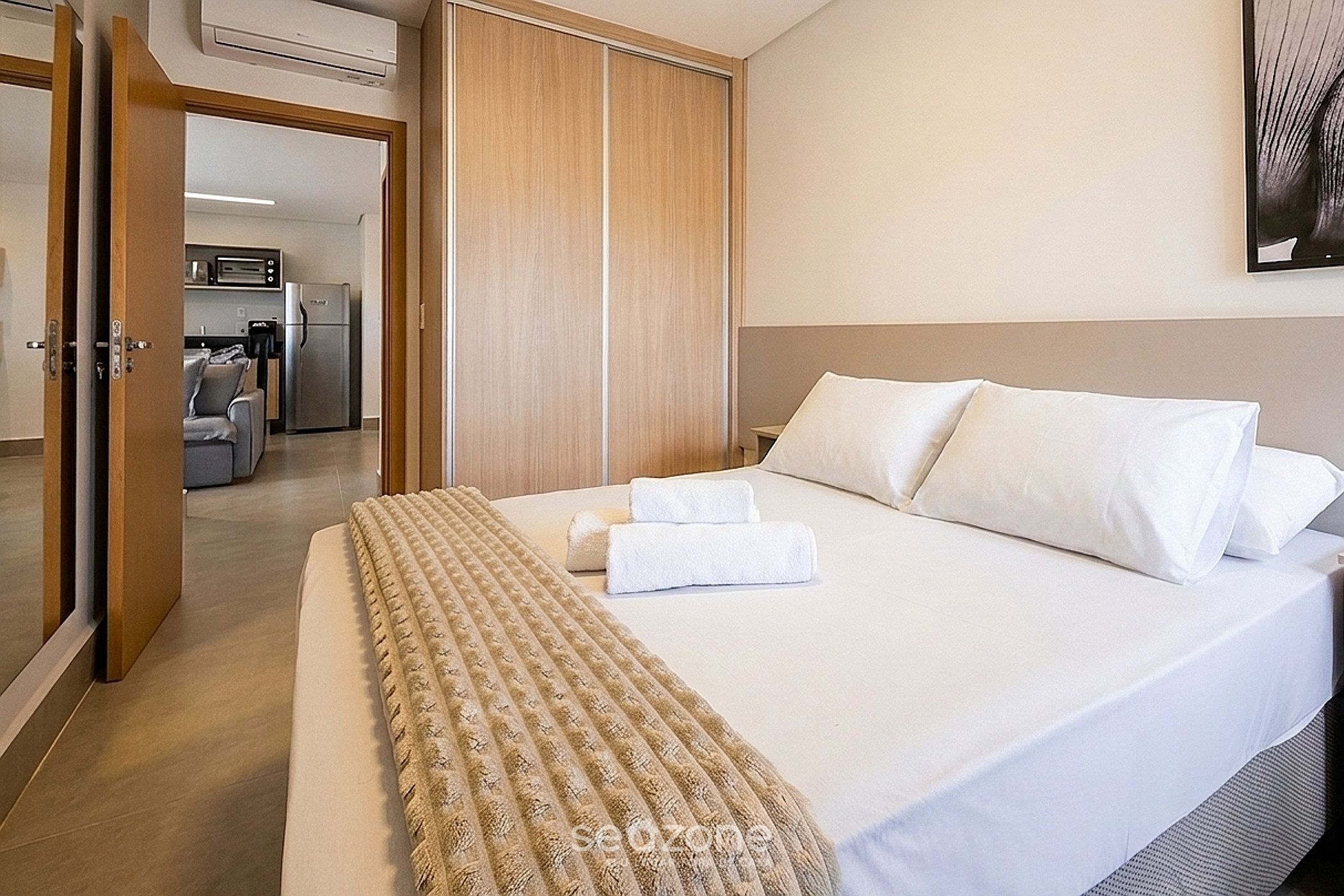 Habitación de hotel con cama, armario, kitchenette y baño.