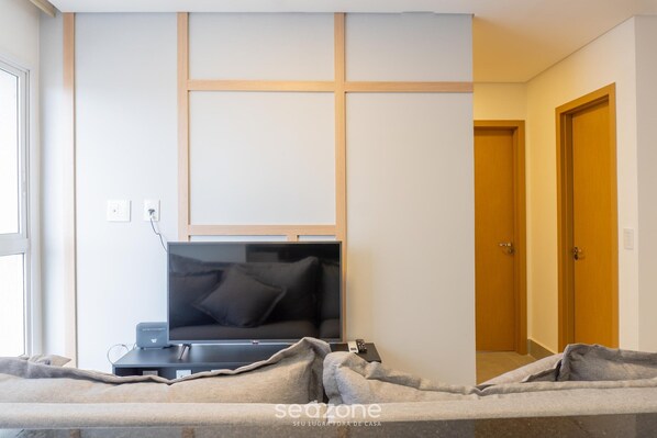 Una habitación con una televisión de pantalla plana montada en la pared, una puerta de madera y una ventana.