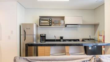 A compact kitchen with a built-in oven, microwave, and coffee maker.