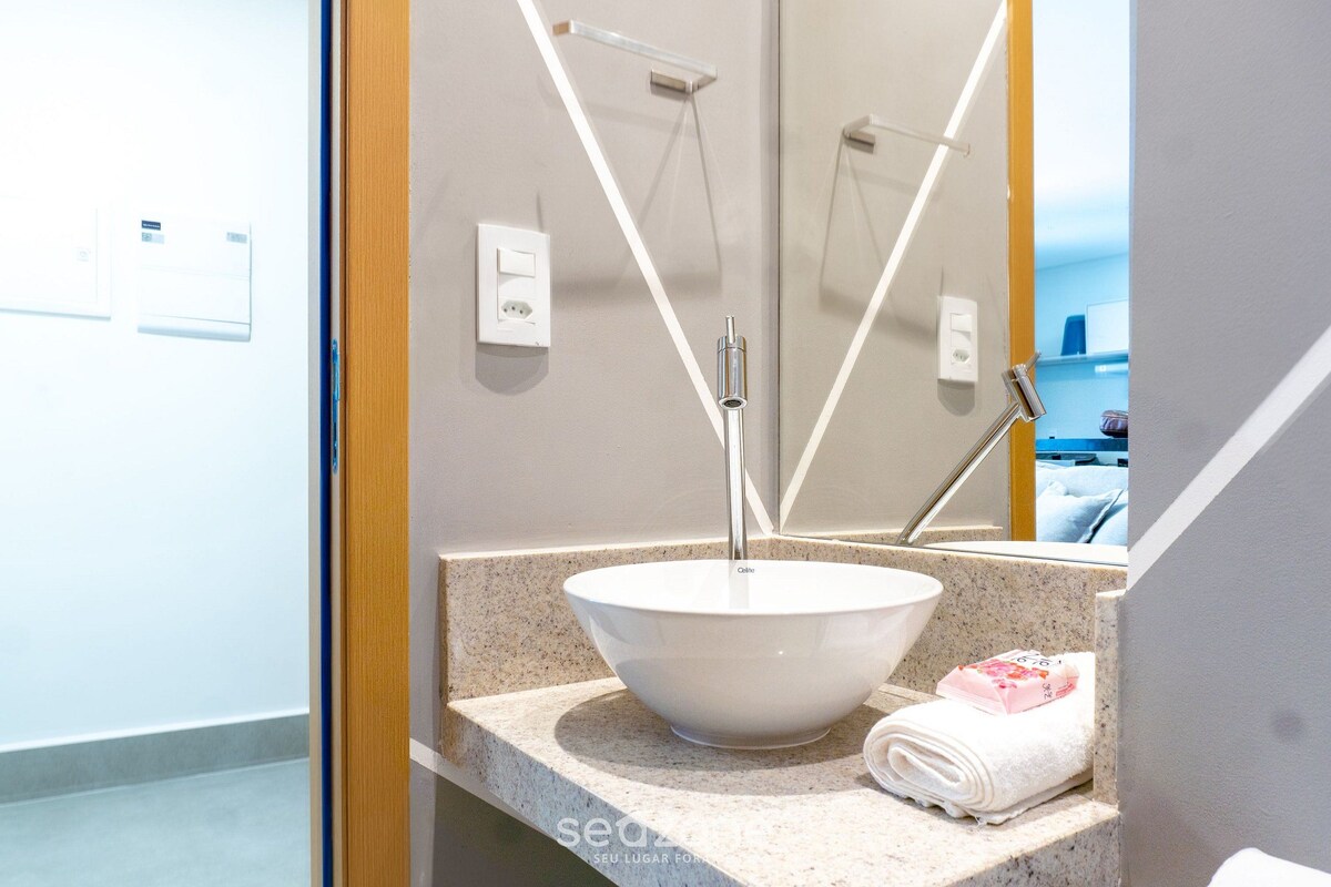 A bathroom with a white sink, a towel, and a mirror.