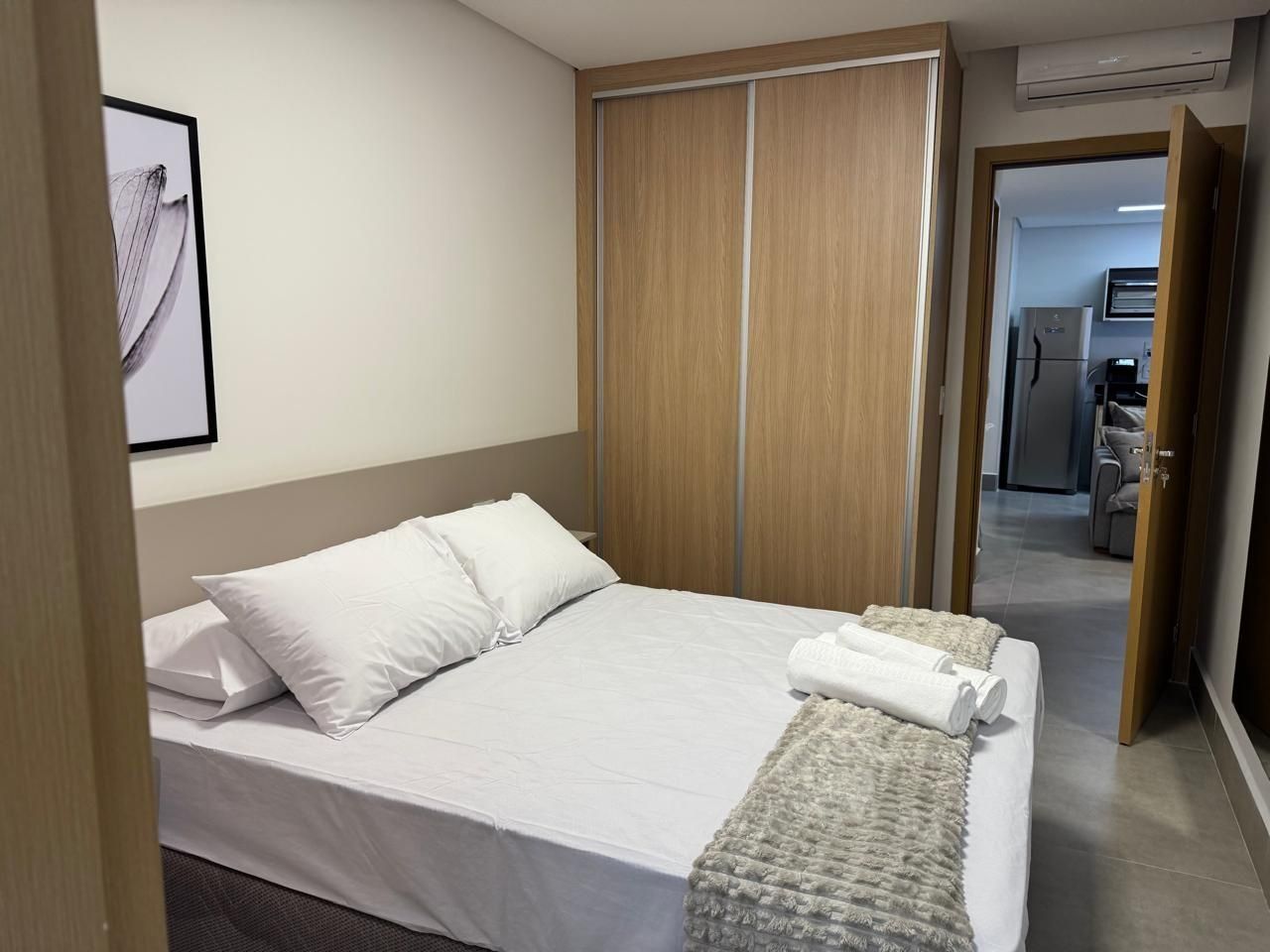 Habitación de hotel con cama, armario y baño visible a través de una puerta abierta.