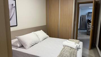 Habitación de hotel con cama, armario y baño visible a través de una puerta abierta.