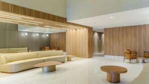 Un hall d’entrée moderne avec un canapé, des tables rondes et un lambris en bois.