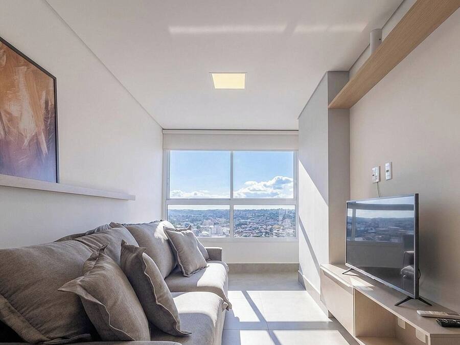 Una sala moderna con un sofá, un televisor de pantalla plana y un amplio ventanal con vista a la ciudad.
