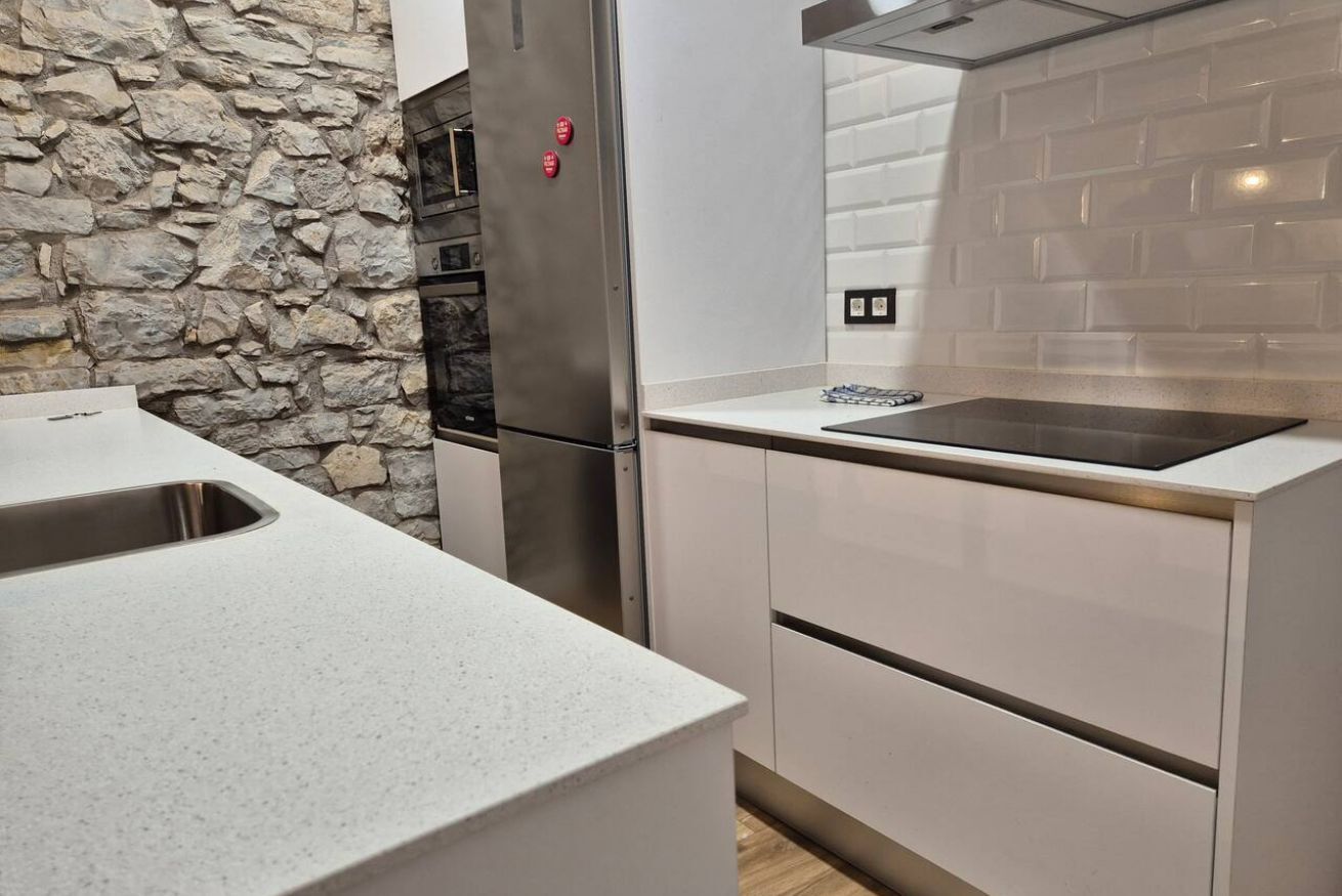 A kitchen with a stone wall, stainless steel appliances, and a modern design.