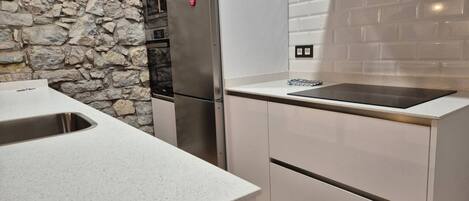 A kitchen with a stone wall, stainless steel appliances, and a modern design.
