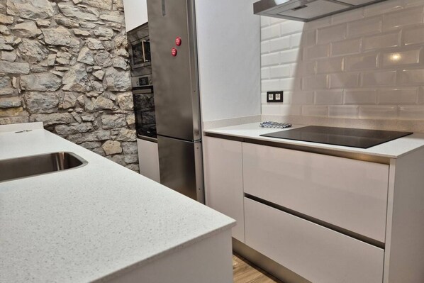 Une cuisine avec un mur en pierre, des appareils électroménagers en acier inoxydable et un design moderne.