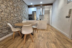 Un coin repas avec un mur en pierre, une table en bois et des chaises blanches.