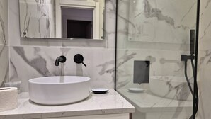 A bathroom with a white marble sink, a mirror above it, and a glass shower enclosure.