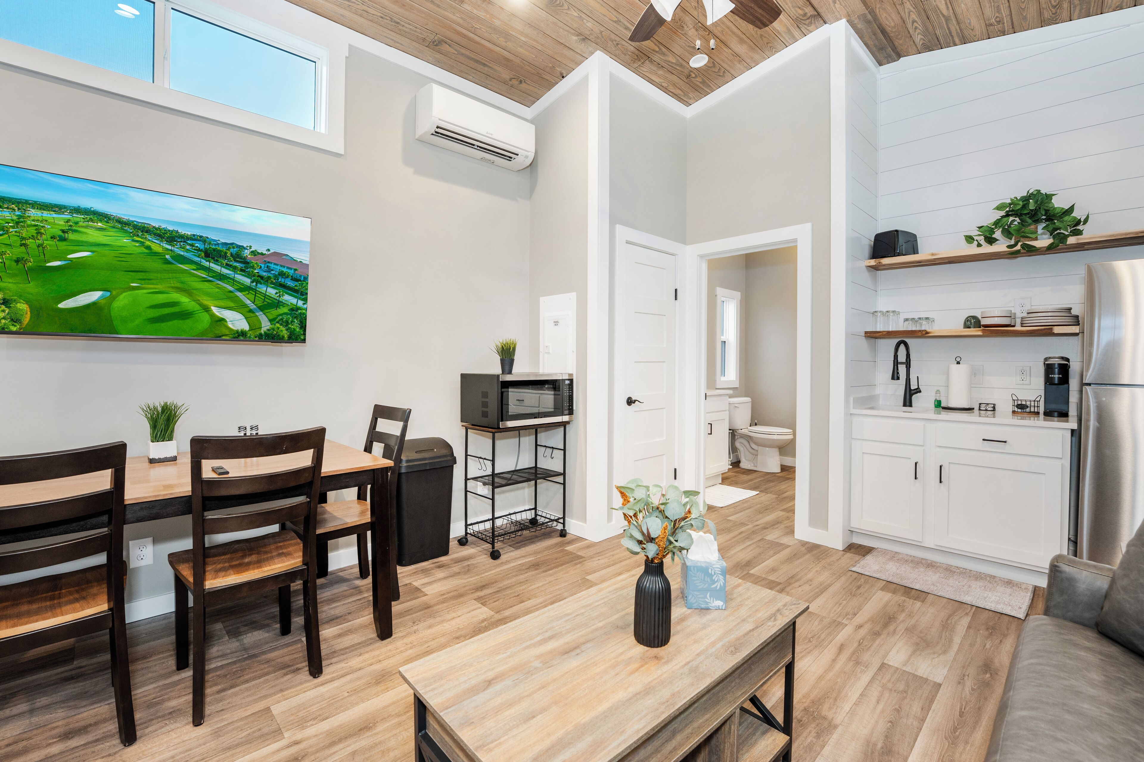 A modern kitchen with white cabinets, a stainless steel refrigerator, and a microwave.