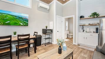 A modern kitchen with white cabinets, a stainless steel refrigerator, and a microwave.