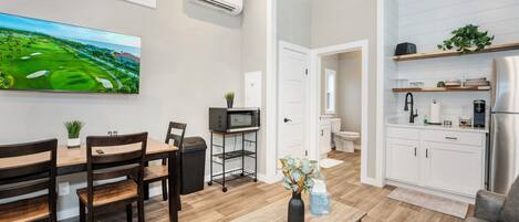 A modern kitchen with white cabinets, a stainless steel refrigerator, and a microwave.