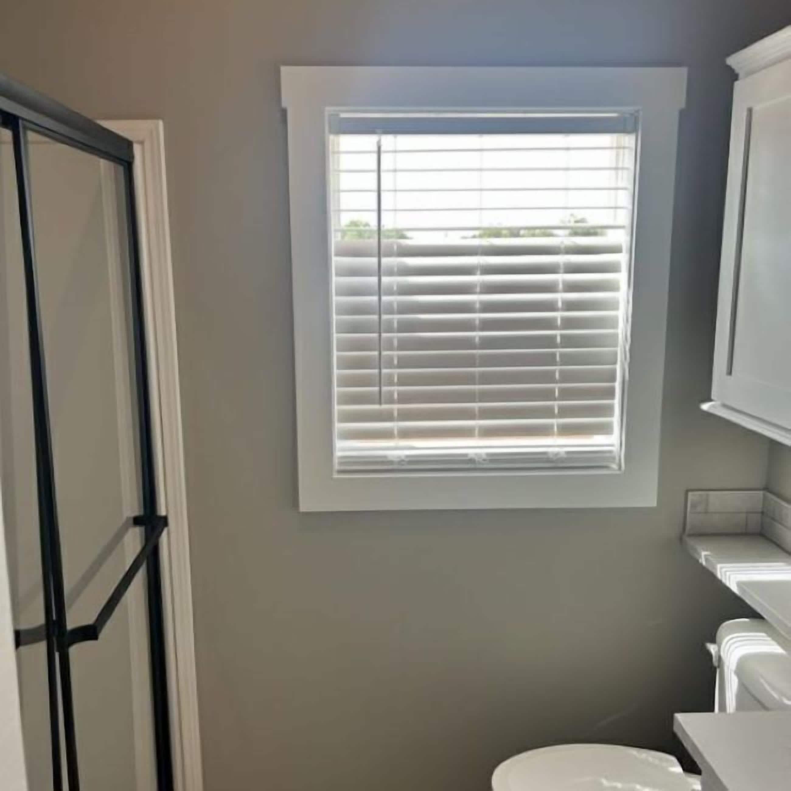 Ein Badezimmer mit Fenster, Toilette und Duschbereich.