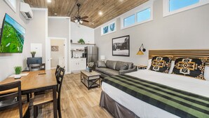A modern bedroom with a large bed, a ceiling fan, and a view of the outdoors through a window. - Carolina Camp Cedar (Pickens)
