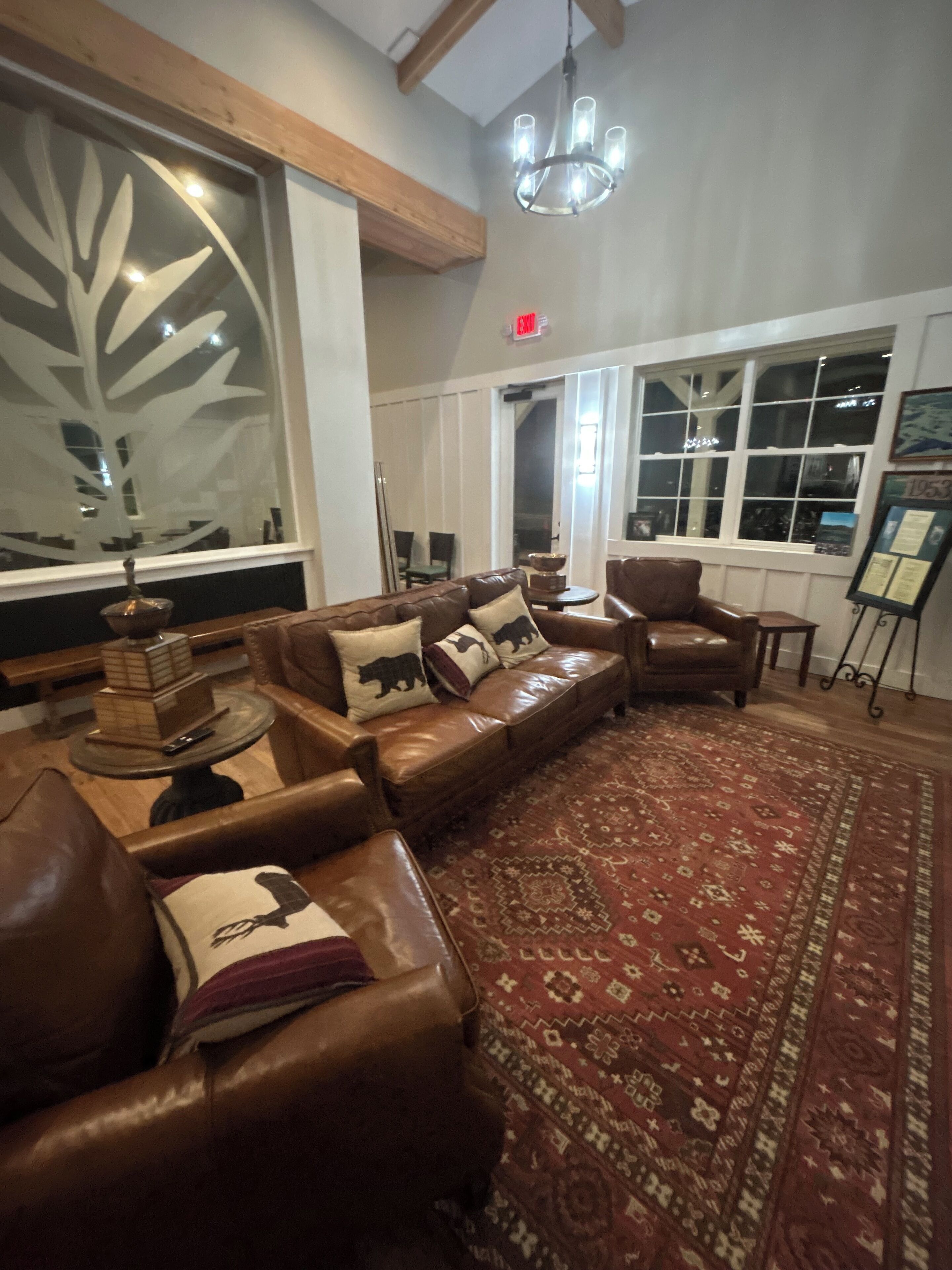 A spacious living room with a large sectional sofa, a patterned rug, and a chandelier.
