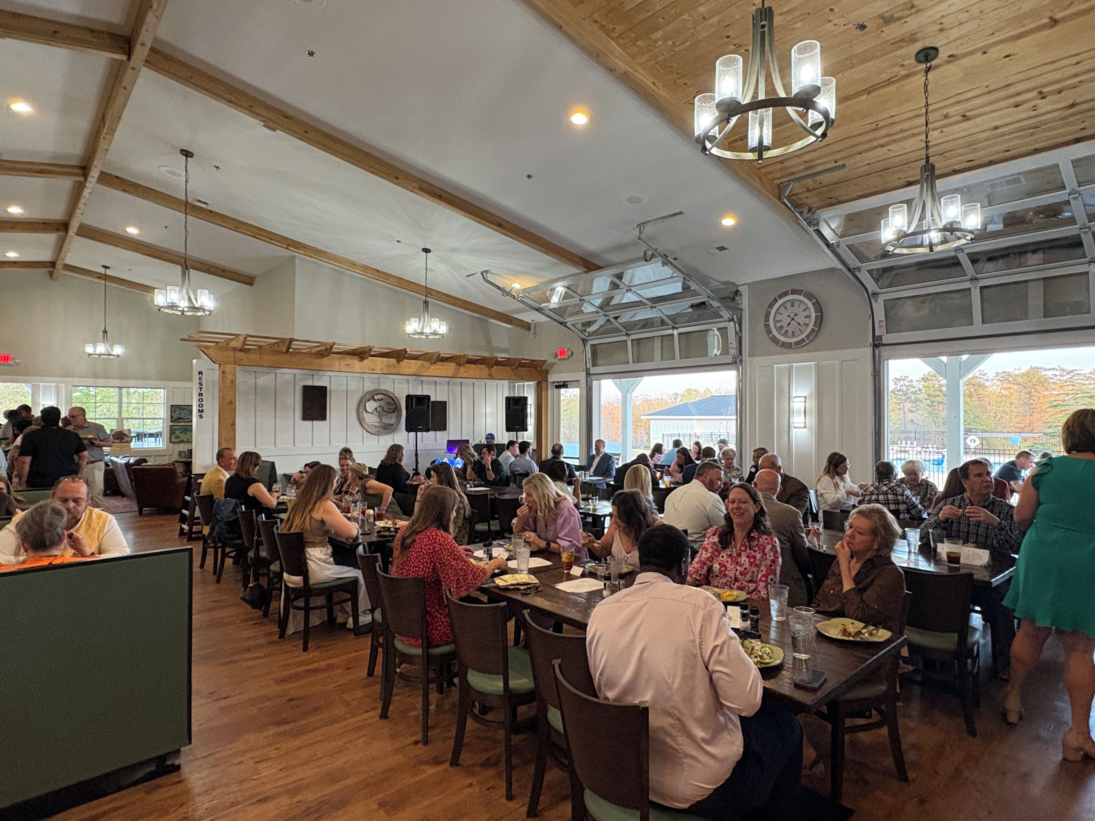 Un vaste espace dédié à la salle à manger, agrémenté de poutres en bois et de lustres, et comprenant plusieurs tables et chaises.