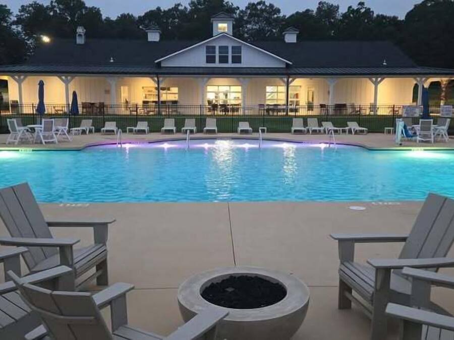 A swimming pool with lounge chairs and a covered area with tables and chairs.