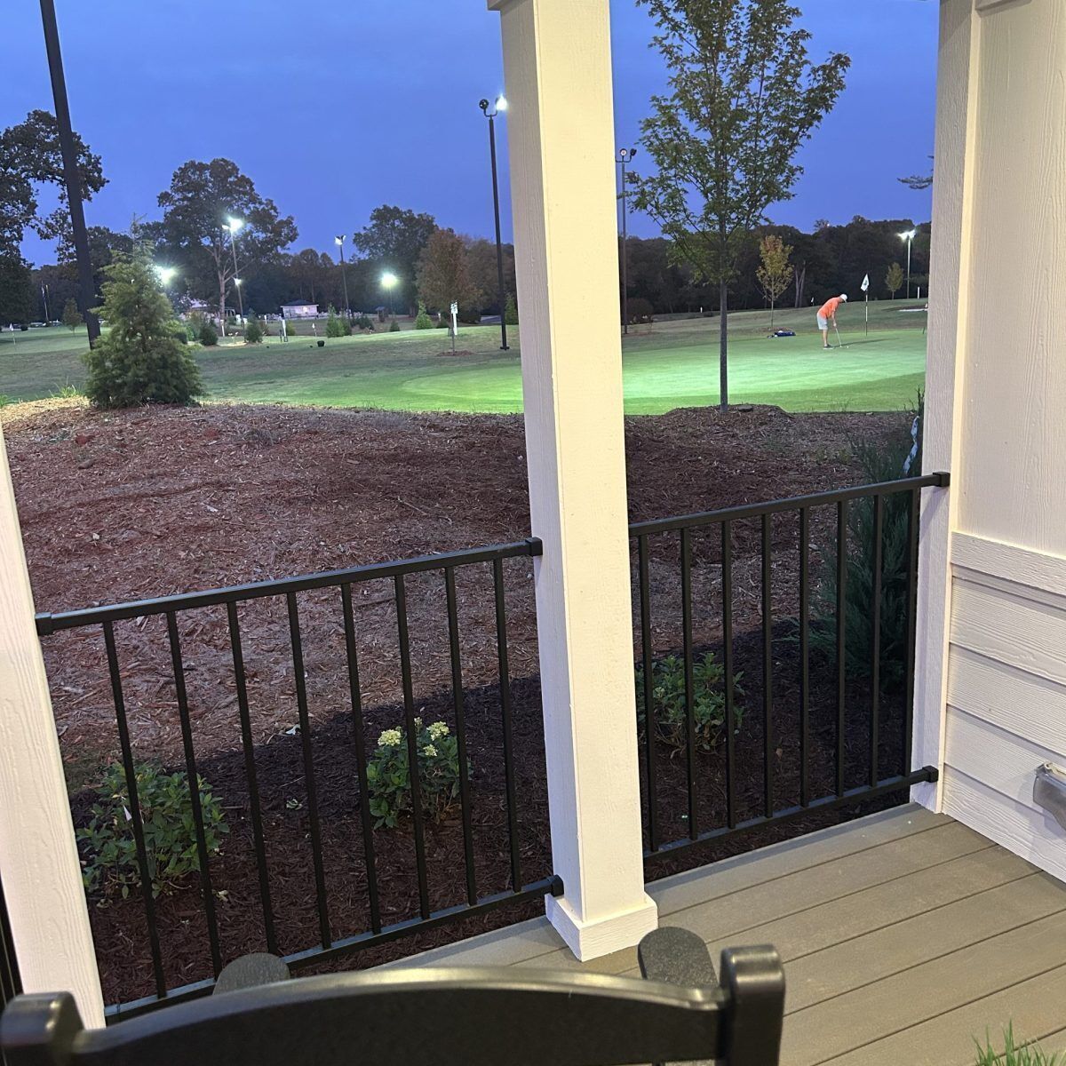 A porch with a view of a golf course at dusk.